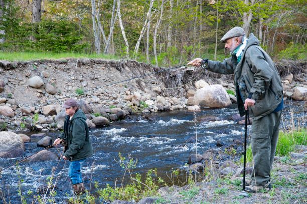 istock A mature man wearing a cervical collar and using a cane while fly fishing.  Real person. With a child. 1319020204