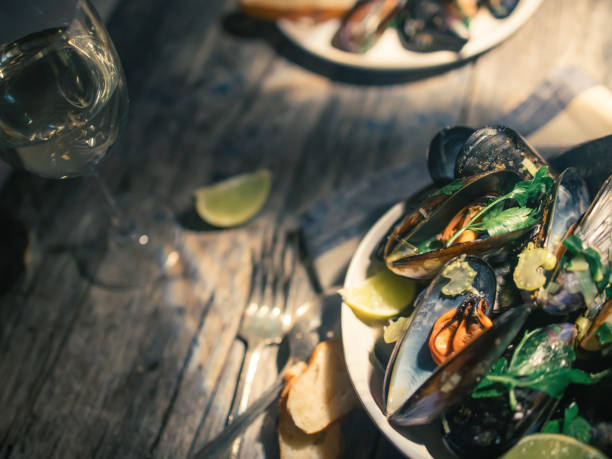 istock Blue mussles with vine and baguette on wooden table 1319020745