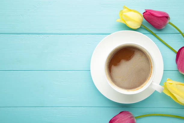 istock Cup of coffee with tulips on blue background 1319020787
