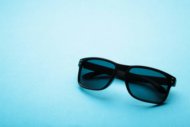 istock Stylish black sunglasses on a blue background with copy space 1319021393