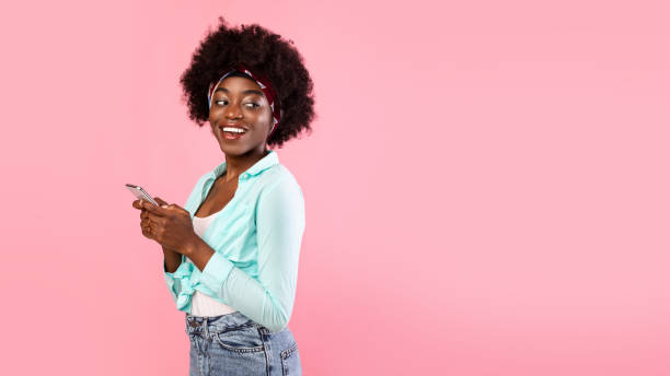 istock Cheerful African Lady Using Smartphone Standing Over Pink Background, Panorama 1319023255