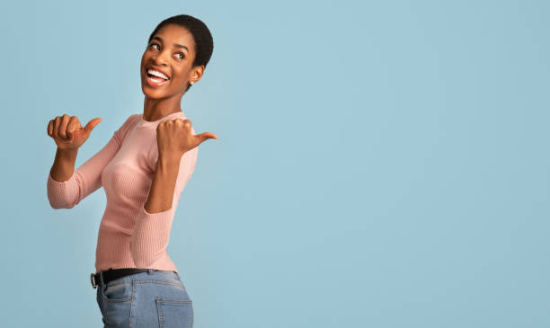 istock Check This. Cheerful African American Female Pointing Back With Two Thumbs Up 1319023505