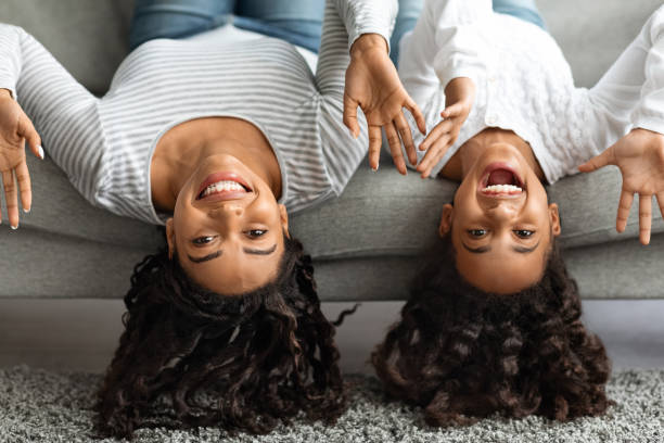 istock Funny mother and daughter laying on couch upside down 1319024192