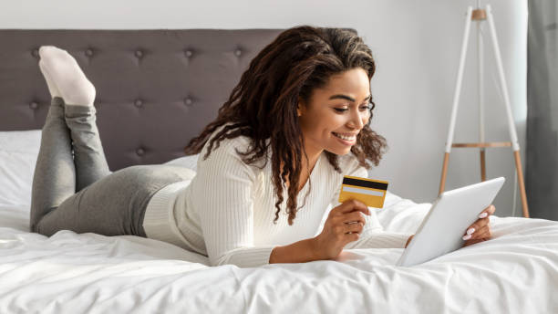 istock Happy black woman holding debit credit card, using tablet 1319024596