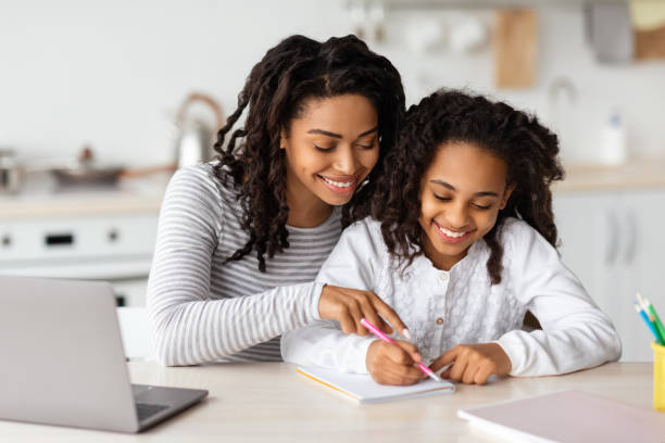 istock Beautiful black mother helping her daughter with homework 1319024782