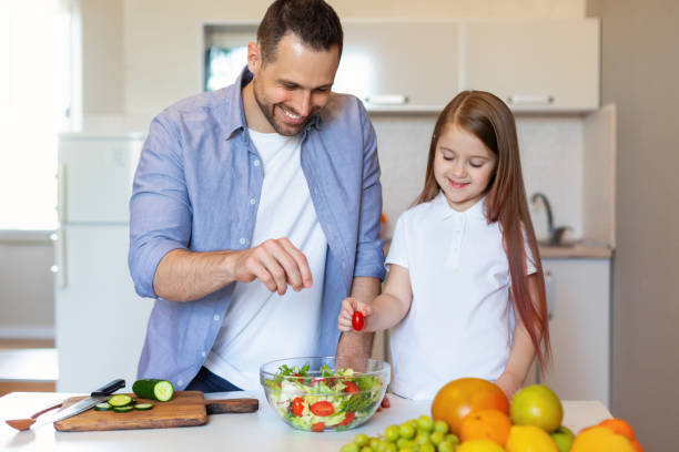 istock Happy Little Girl Cooking With Daddy Preparing Salad In Kitchen 1319025764