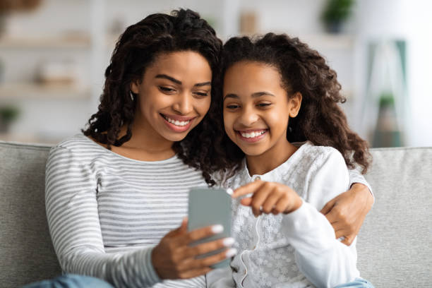 istock Happy african american mother and kid using smartphone together 1319025964