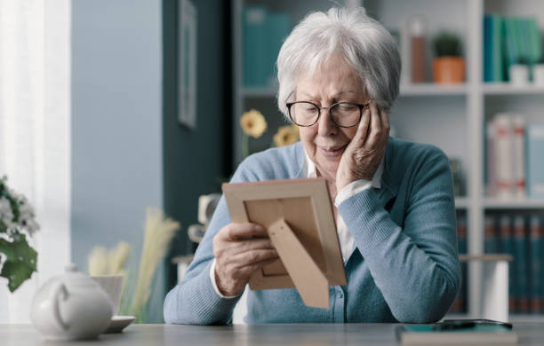 Sad old woman mourning the loss of her husband Sad senior woman mourning the loss of her husband, she is holding a picture and crying widow stock pictures, royalty-free photos & images