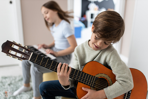 Brother and sister playing instruments at home