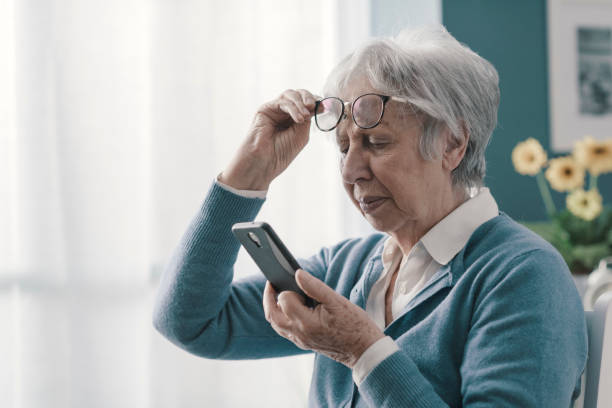 Senior woman having vision problems Senior woman having vision problems, she can't read the messages on her smartphone myopia stock pictures, royalty-free photos & images