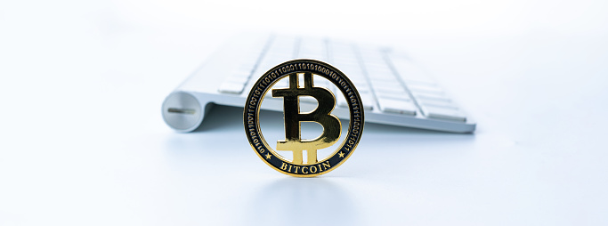 Trade bitcoin. Golden Bit Coin virtual cryptocurrency or blockchain technology. Gold Crypto currency BTC Bitcoin with keyboard on white background. Block chain, network connect concept