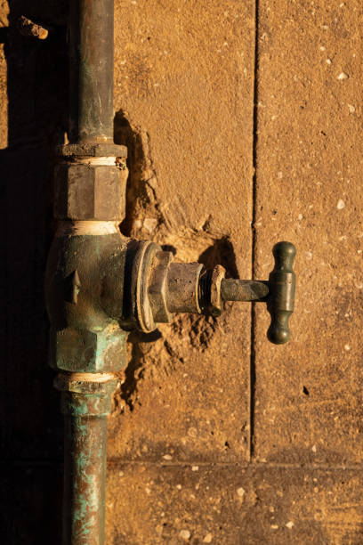 rubinetto e pipa arrugginiti vecchio su un muro al sole del pomeriggio - water pipe rusty dirty equipment foto e immagini stock
