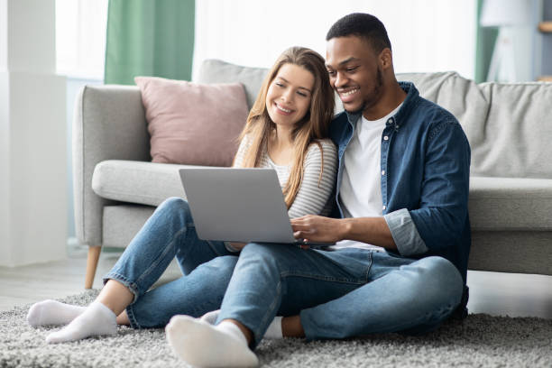 istock Cheerful Millennial Mixed Couple Spending Time With Laptop At Home 1319029559