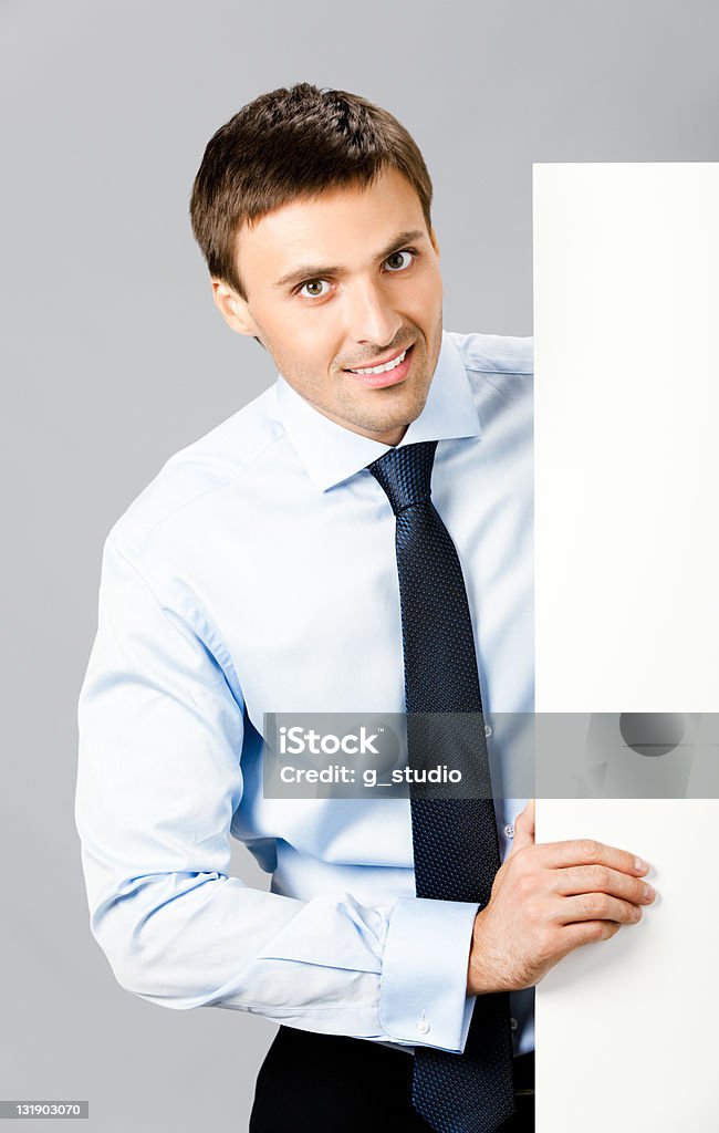 Homem de negócios, mostrando placa em branco, no cinza - Foto de stock de Adulto royalty-free