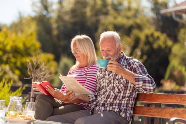 istock Senior couple drinking morning coffee and reading in the backyard 1319030954