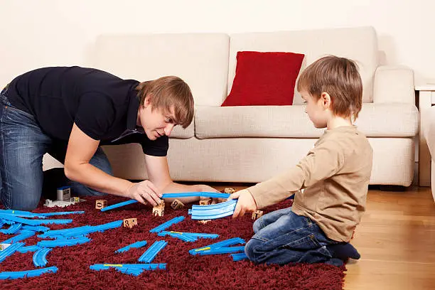 Father is playing with son in toy railroad