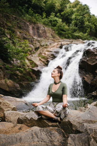 donna seduta di fronte alla cascata - waterfall zen like women meditating foto e immagini stock