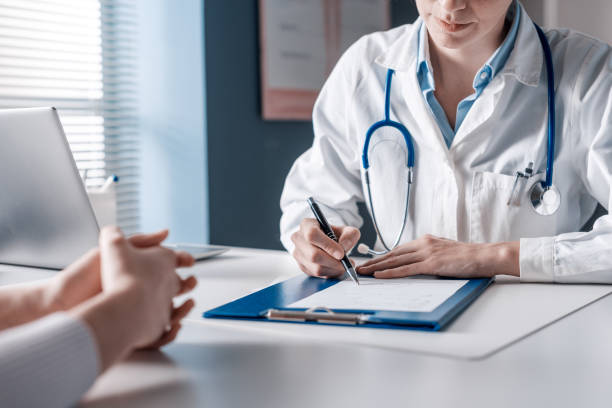 Doctor writing a medical prescription Doctor sitting at desk and writing a prescription for her patient consulting doctor stock pictures, royalty-free photos & images