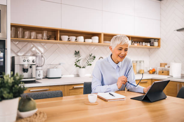 istock Beautiful older woman working from home, having online conference. 1319033984