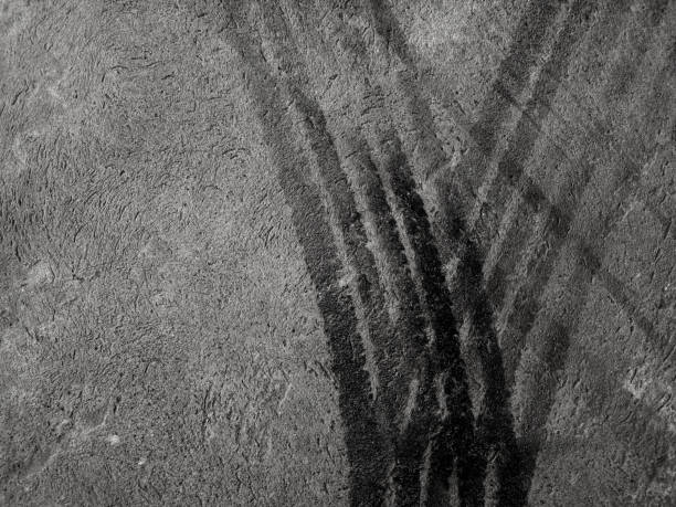 Close up black tire marks on cement floor. Abstract concrete texture in vintage style. Dark background for graphic design or wallpaper. Stains on the road surface caused by the wheels of the car.