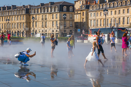 Girl in tutu dancing on the Mirroir d'eau (Water Mirror) of the Place de la Bourse in Bordeaux France on a hot summer day during a heat wave