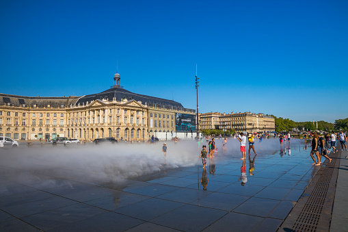 Tourists and kids having fun on the Mirroir d'eau (Water Mirror) of the Place de la Bourse in Bordeaux France