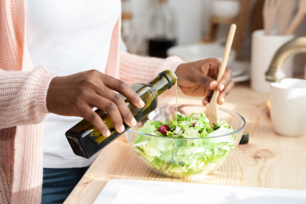 nutrition saine. femme noire méconnaissable cuisinant une salade de légumes frais dans la cuisine - black olive photos et images de collection