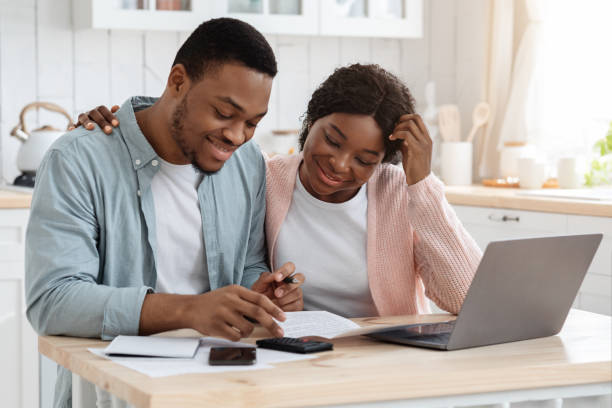 портрет счастливых чернокожих супругов чтение страховых документов на дому - loan house calculator currency стоковые фото и изображения