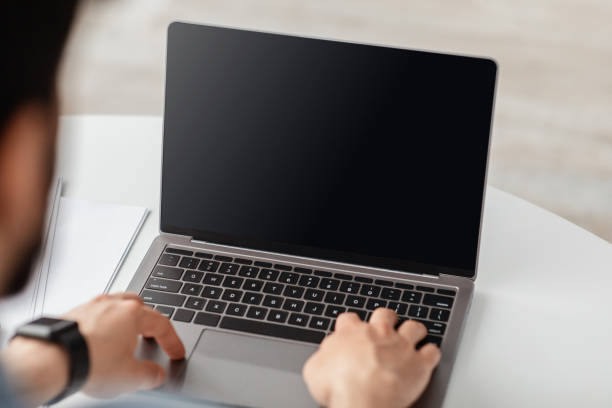 istock Lifestyle and gadgets concept. Unrecognizable adult man using laptop with blank black screen for mockup template 1319037848