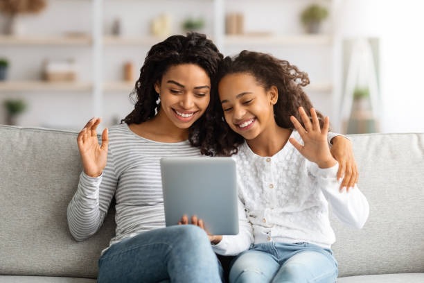istock Smiling black mother and daughter having video call on tablet 1319040151