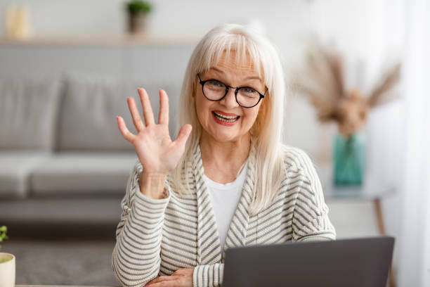 istock Mature woman having video call using laptop and waving 1319041851