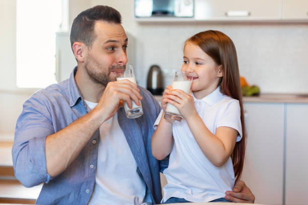 istock Little Daughter And Father Drinking Milk Enjoying Taste In Kitchen 1319042092