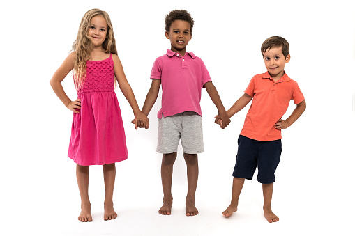 Three children stand in front of a white background