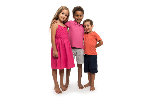 Three children stand in front of a white background