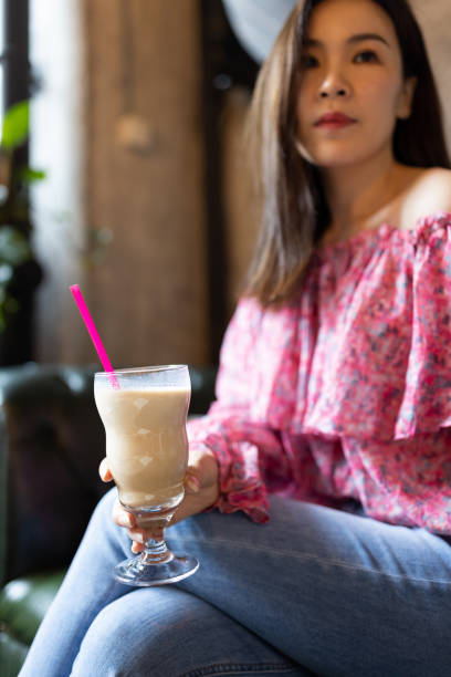 istock Pretty young asian woman drinking iced coffee in modern cafe 1319043395