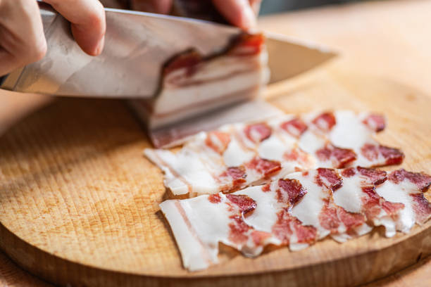 pancetta chopped into thin slices using sharp knife - pancetta imagens e fotografias de stock