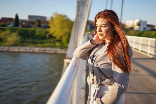 istock Young redhead woman standing on bridge and looking away 1319045654