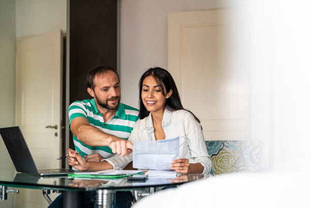 istock Happy couple sitting together at home using laptop and doing online payments 1319049174