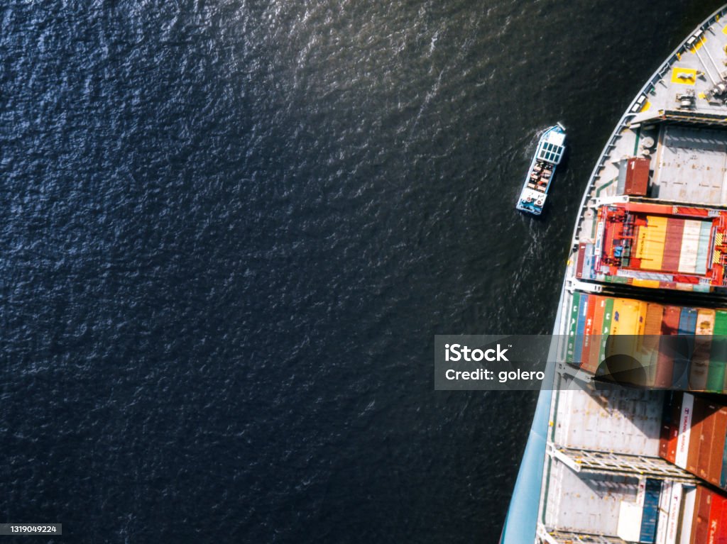 tiny ship beside huge container freight ship high angle view on huge Cargo container ship beside tiny ship passing beside Small Stock Photo