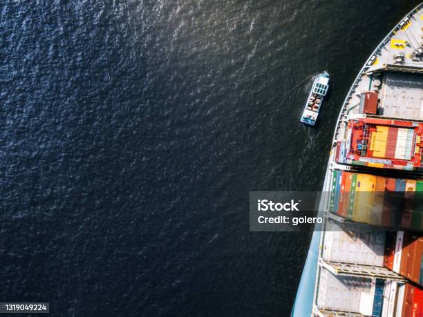 Tiny Ship Beside Huge Container Freight Ship Stock Photo - Download Image Now - Small, Large, Ship