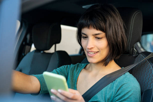 istock Smiling woman checking location on mobile phone while sitting in car 1319050123