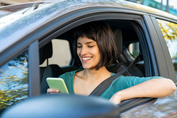Contented mid adult woman using mobile phone while sitting in driver´s seat in car stock photo