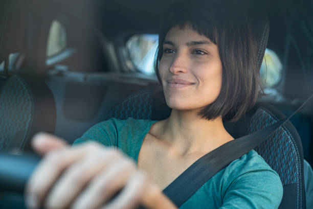 donna contenta guardando attraverso il ventohiled durante la guida - woman driver foto e immagini stock