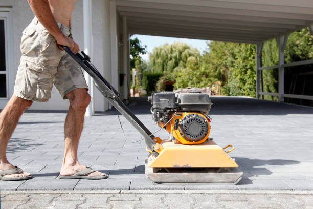 istock Male Worker using vibratory plate compactor to firm soil at worksite. builder. After laying of paving slabs, compacts paving stones with a gasoline vibratory compactor for subsequent. 1319050445