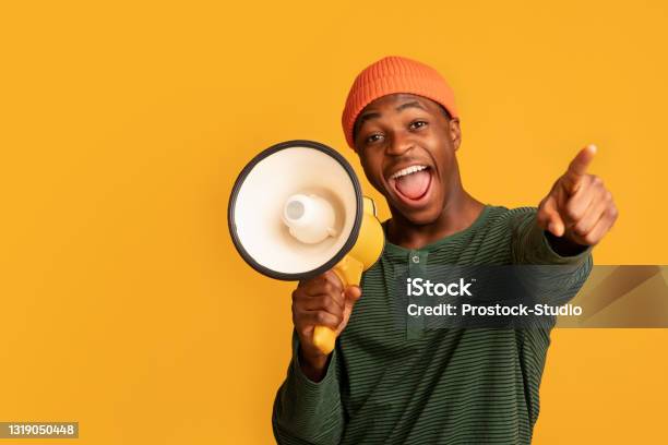 Cheerful Black Guy Shouting In Loudspeaker And Pointing At Camera Stock Photo - Download Image Now