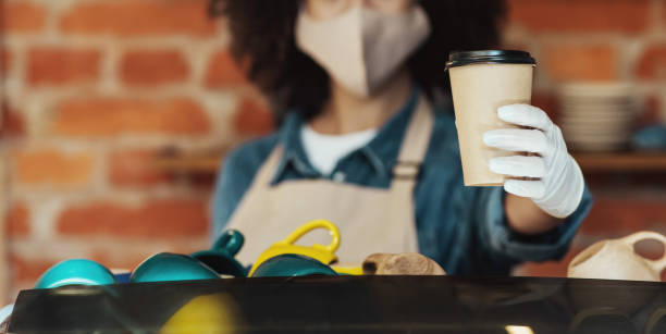 istock Coffee shop worker offering takeout drink, safe restaurant take away delivery 1319050612