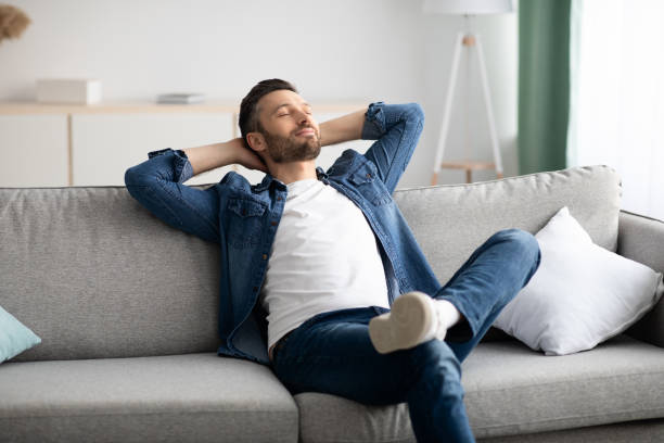 istock Happy bearded man relaxing on sofa at home 1319052391