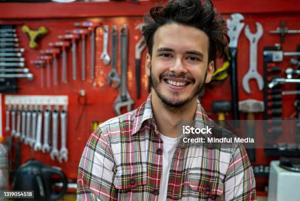 Smiling Young Repair Mechanic Standing With Arms Crossed In Bicycle Repair Shop Stock Photo - Download Image Now