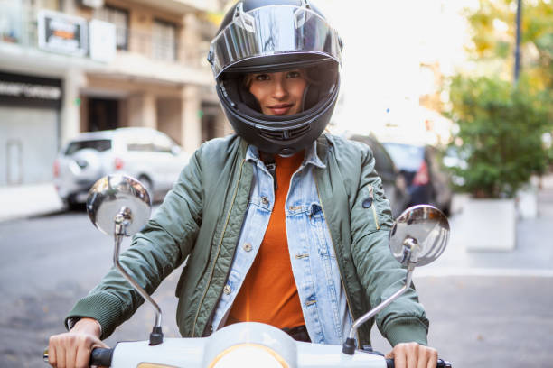 Portrait of smiling woman wearing crash helmet while sitting on motorcycle on the street during daytime stock photo