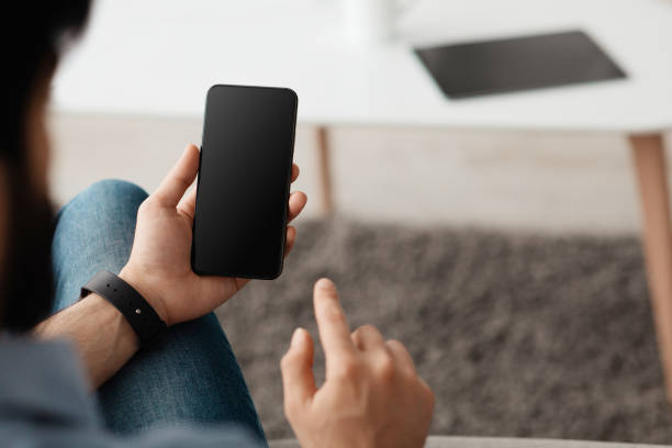 istock Over the shoulder view of unrecognizable man using cellphone with empty black screen for mockup 1319055679